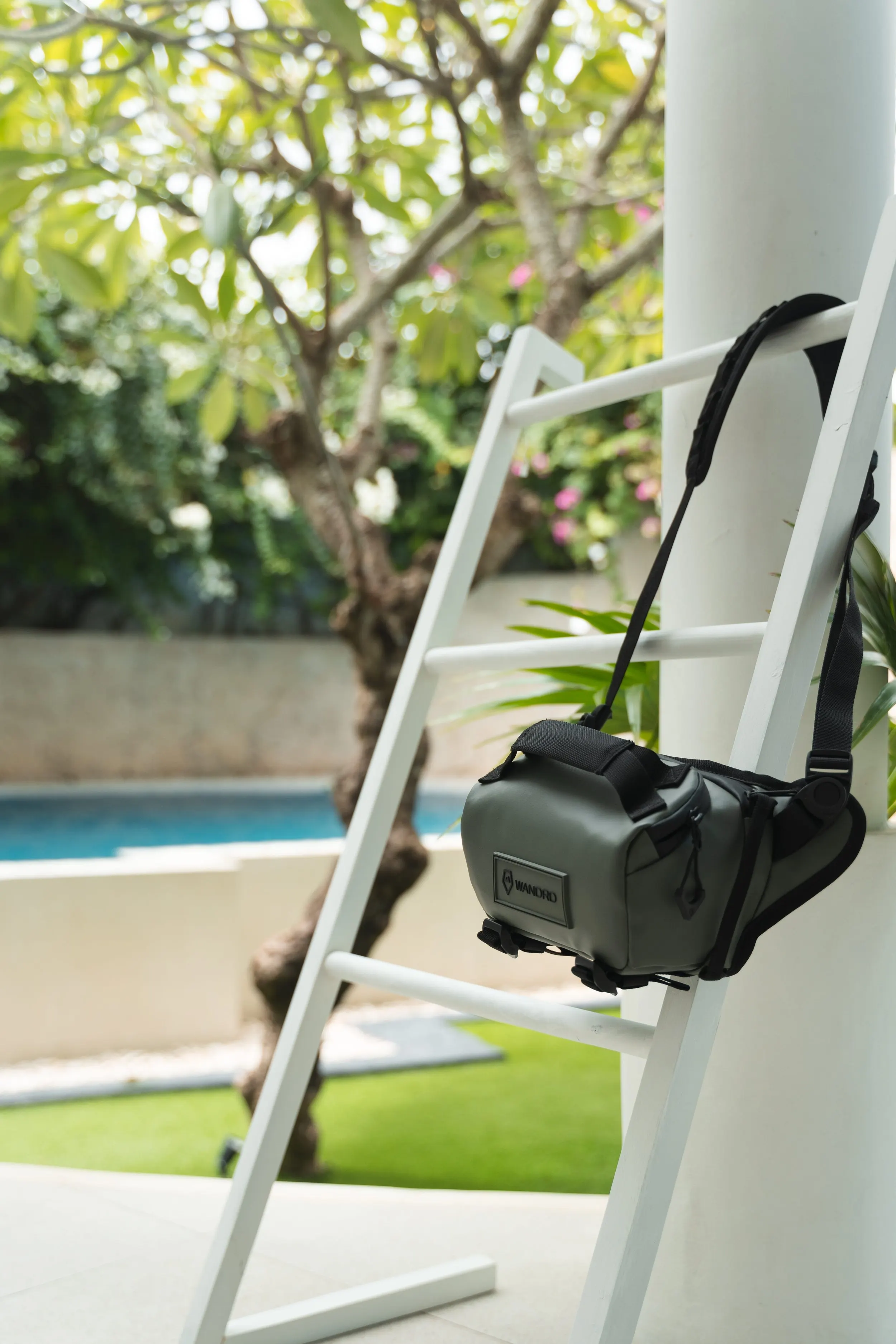 green sling bag hanging on white ladder