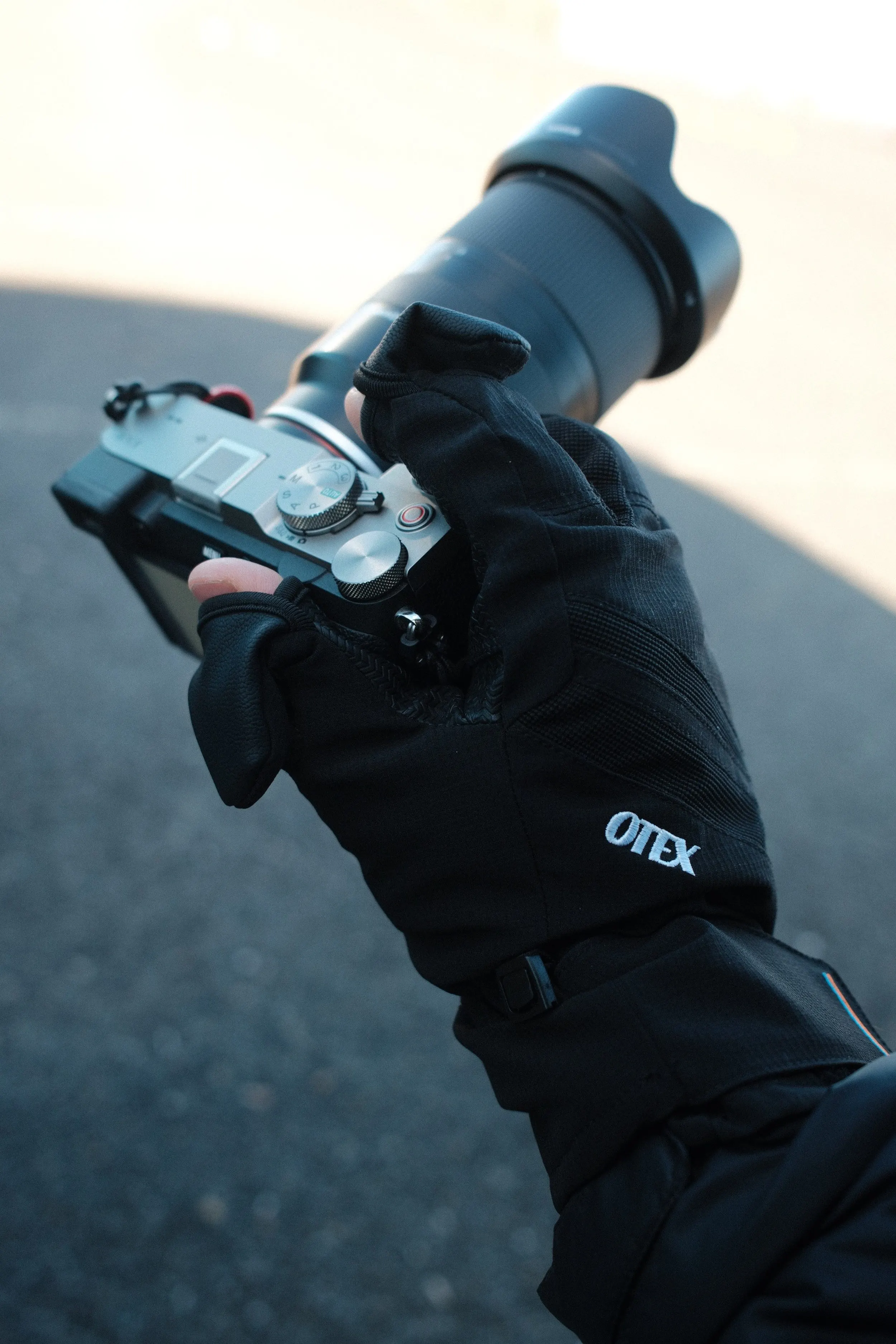Otex XT-850 photography gloves with flip-back fingertips holding a Sony mirrorless camera