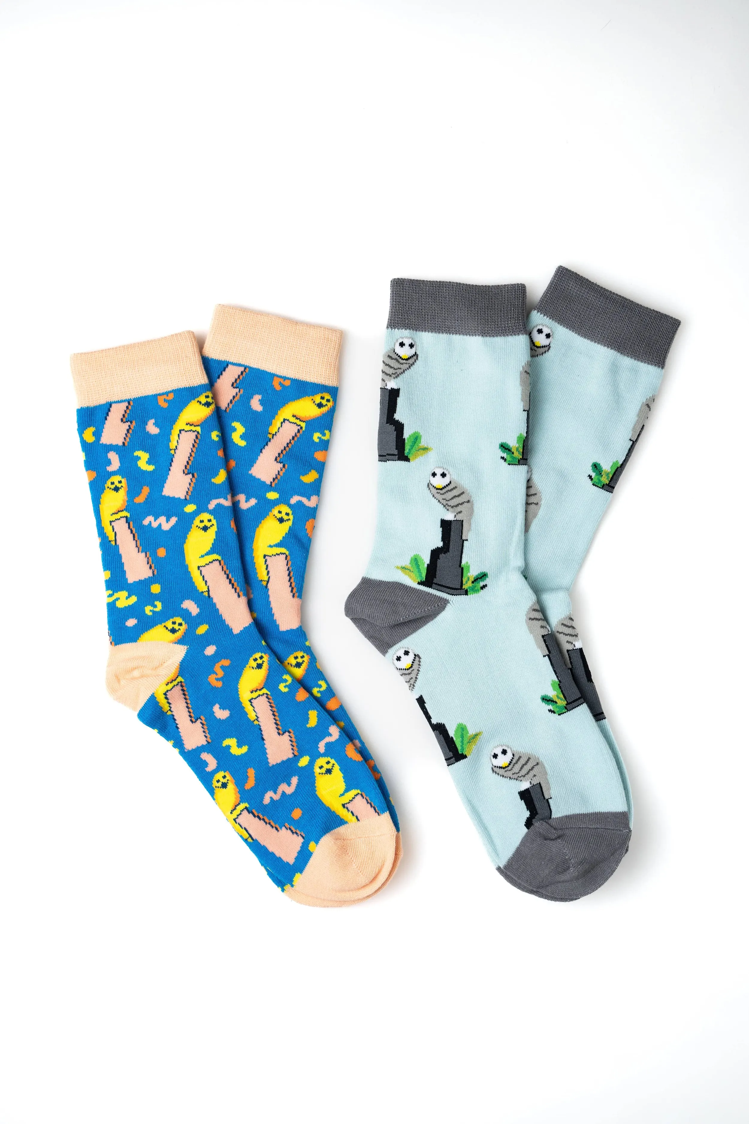 Two pairs of colorful cartoon-themed socks on a white background, one featuring yellow smiley faces and pink ice cream cones on a blue background, the other illustrating grey and white pandas on a light blue background.