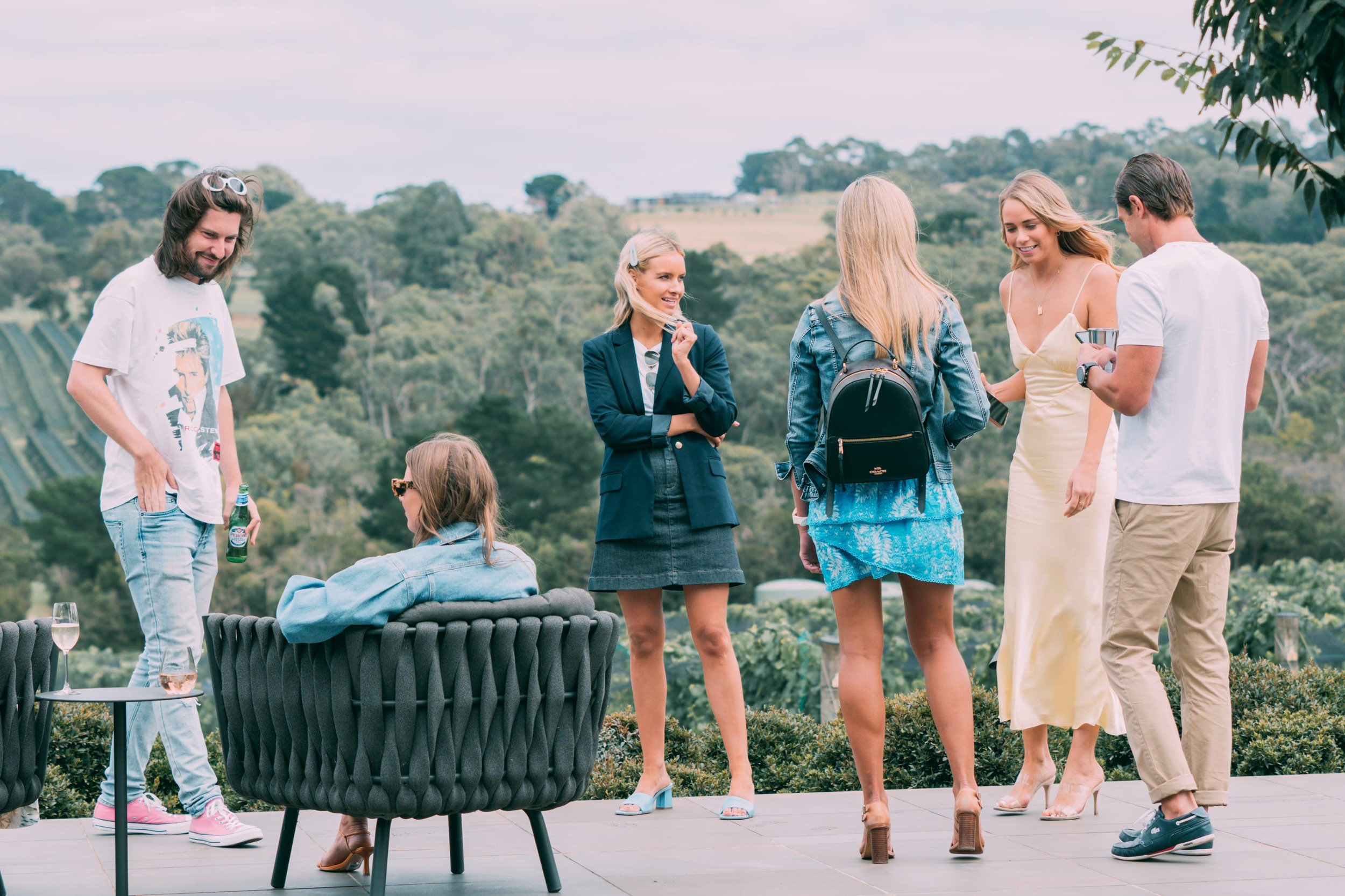 Guests talking on a terrace above rolling vineyards at an outdoor event