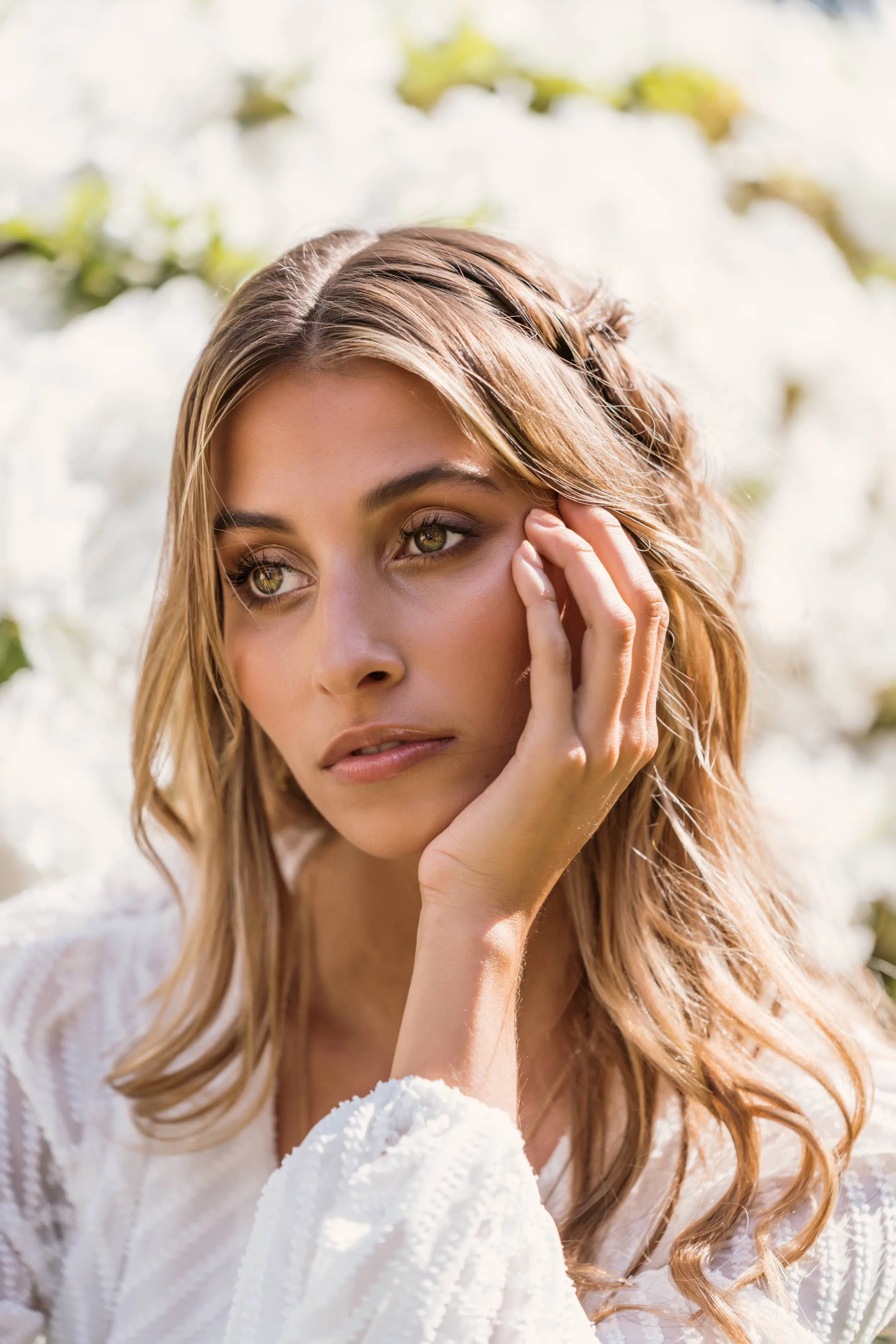 Portrait of a model with long wavy hair, hand resting on her cheek