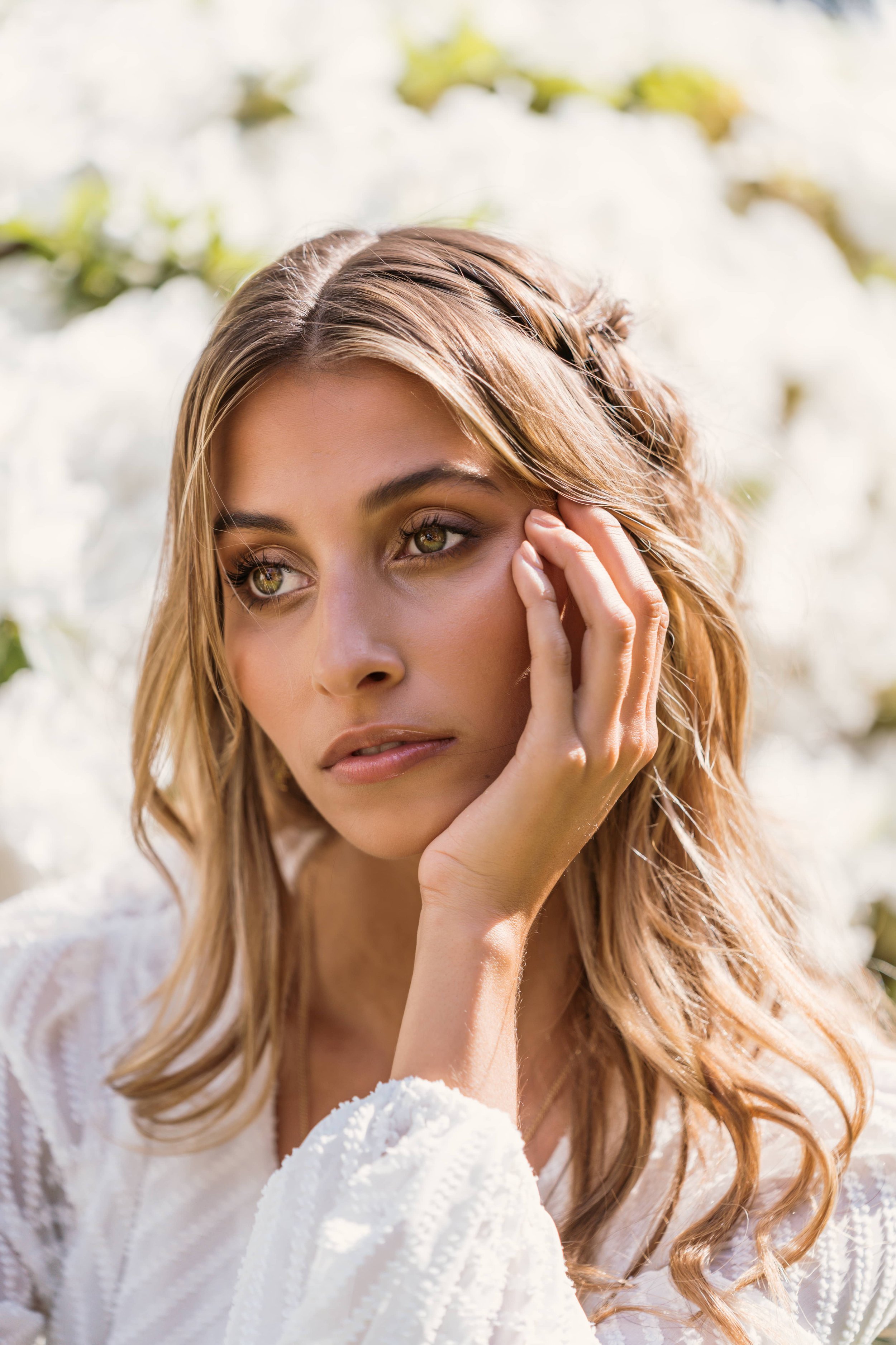 Portrait of a model with long wavy hair, hand resting on her cheek
