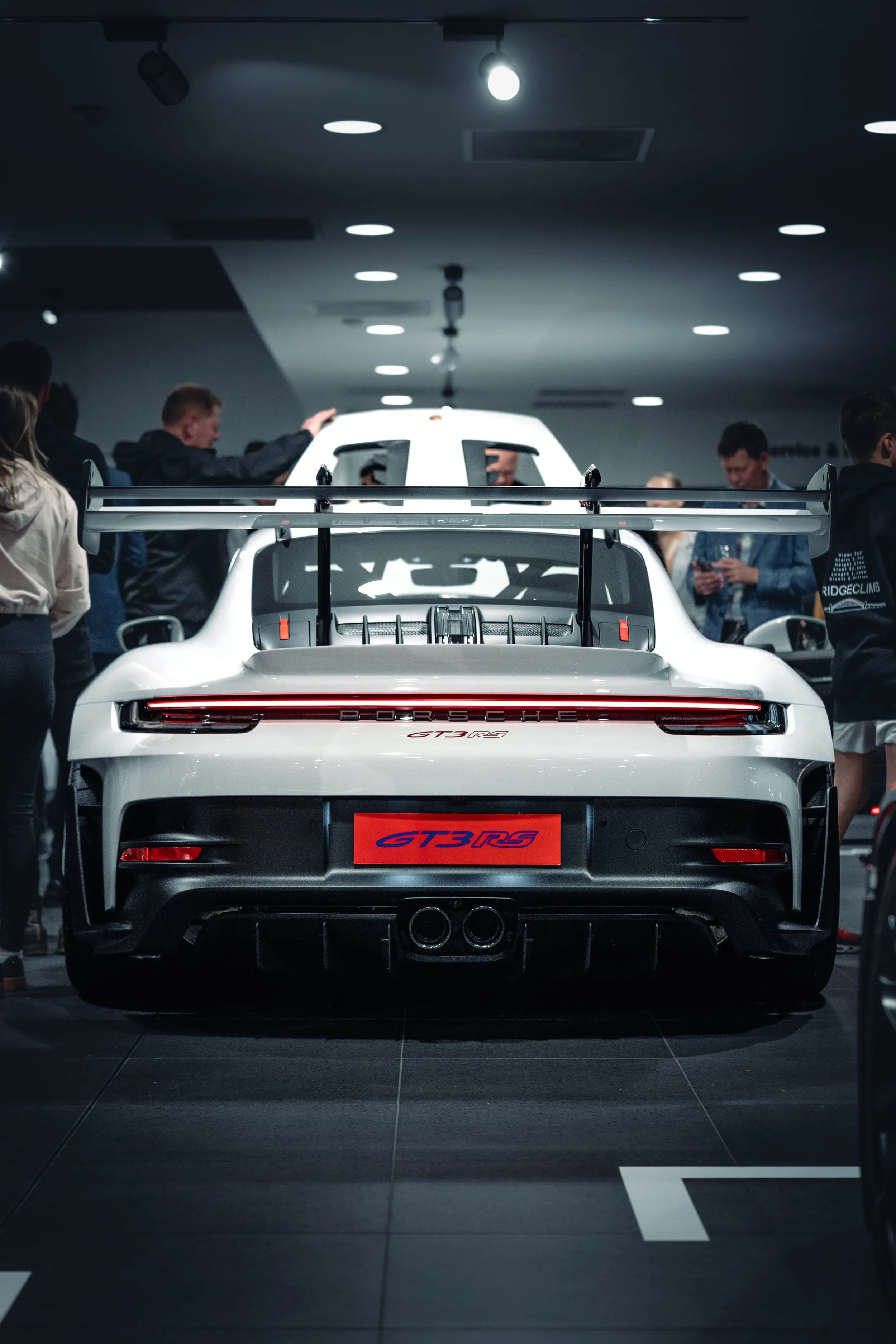 Rear of a white Porsche 911 GT3 RS with its large wing at a showroom launch