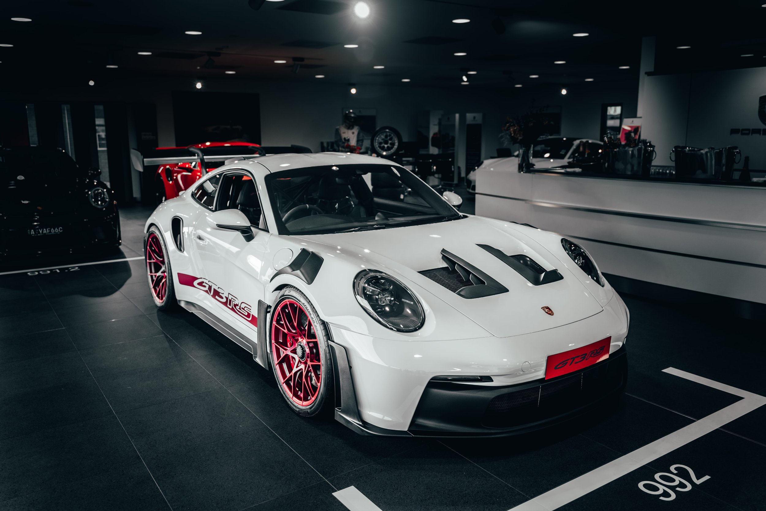 White Porsche 911 GT3 RS on display in a dark showroom